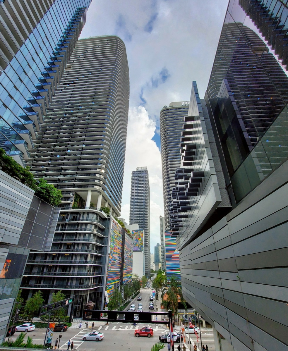 Curved-tower Brickell condominium towers from street level, looking up between modern high-rises
