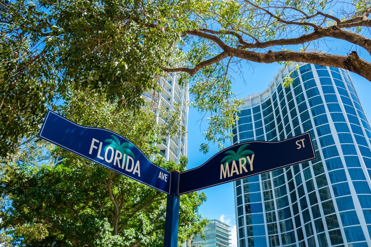Navy and gold Coconut Grove street signs reading FLORIDA AVE and MARY ST in front of a high-rise condominium
