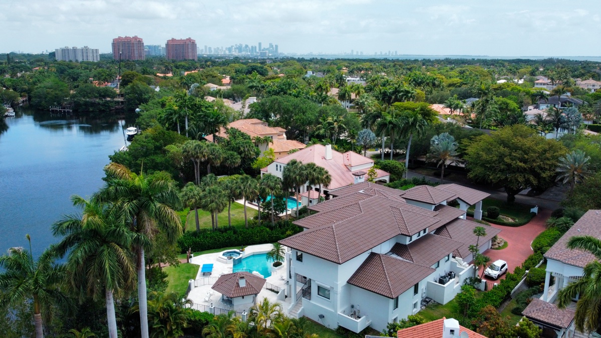 Aerial view of canal-front Coral Gables homes with the Coral Gables skyline in the distance